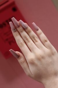 Elegant manicured nails with glitter accent for beauty and style.